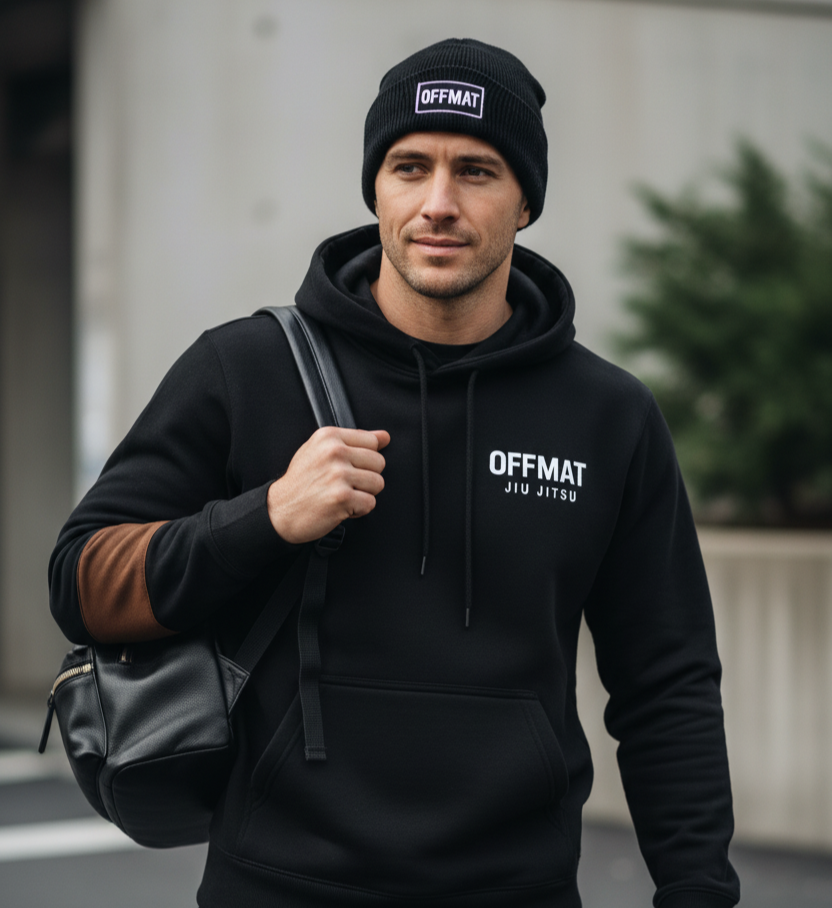 Man wearing a black hoodie and beanie with 'OFFMAT' branding, holding a backpack.